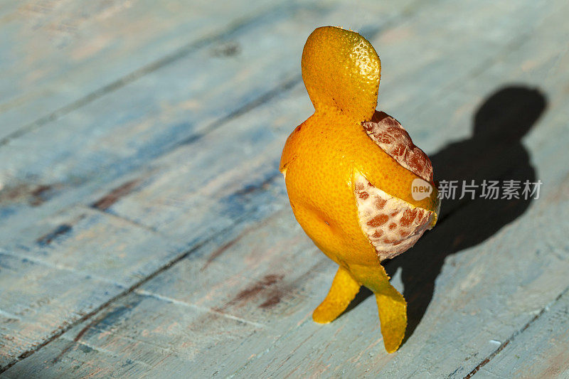 概念-振作起来，继续前进，一个橘子形状的男人带着他自己，在木蓝色背景上的mandarin - man。